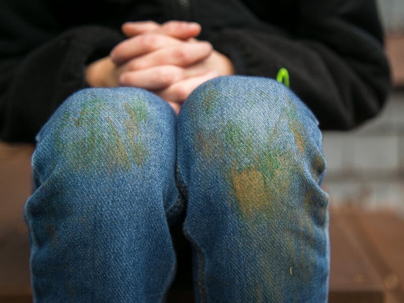 Child with dirty jeans and clasped hands.