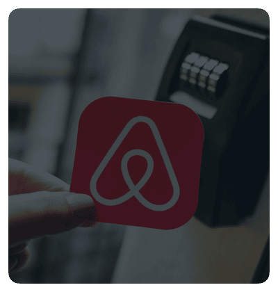 Hand holding Airbnb logo near a keypad lock.